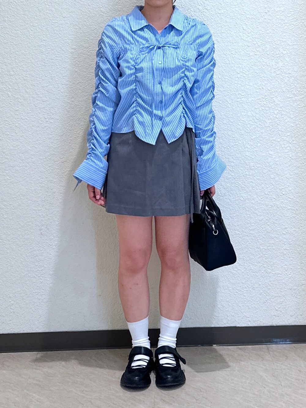 グレー系のスカート、ブルー系のシャツ/ブラウス、ブラック系のトートバッグを着用したレディースの春コーディネートの2枚目の写真