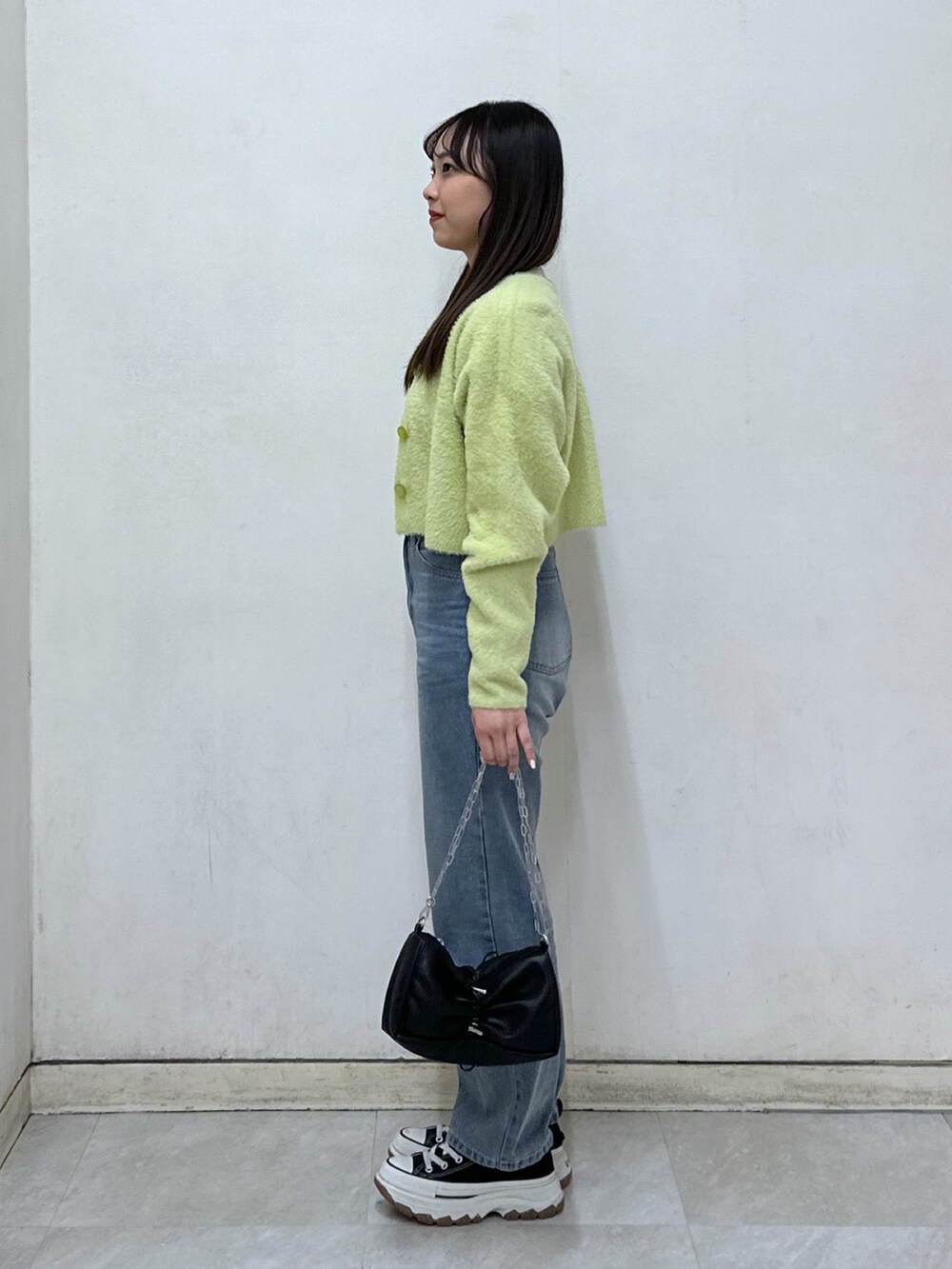 ホワイト系のニット/セーター、グリーン系のカーディガン/ボレロ、ブラック系のハンドバッグを着用したレディースの冬コーディネートの2枚目の写真