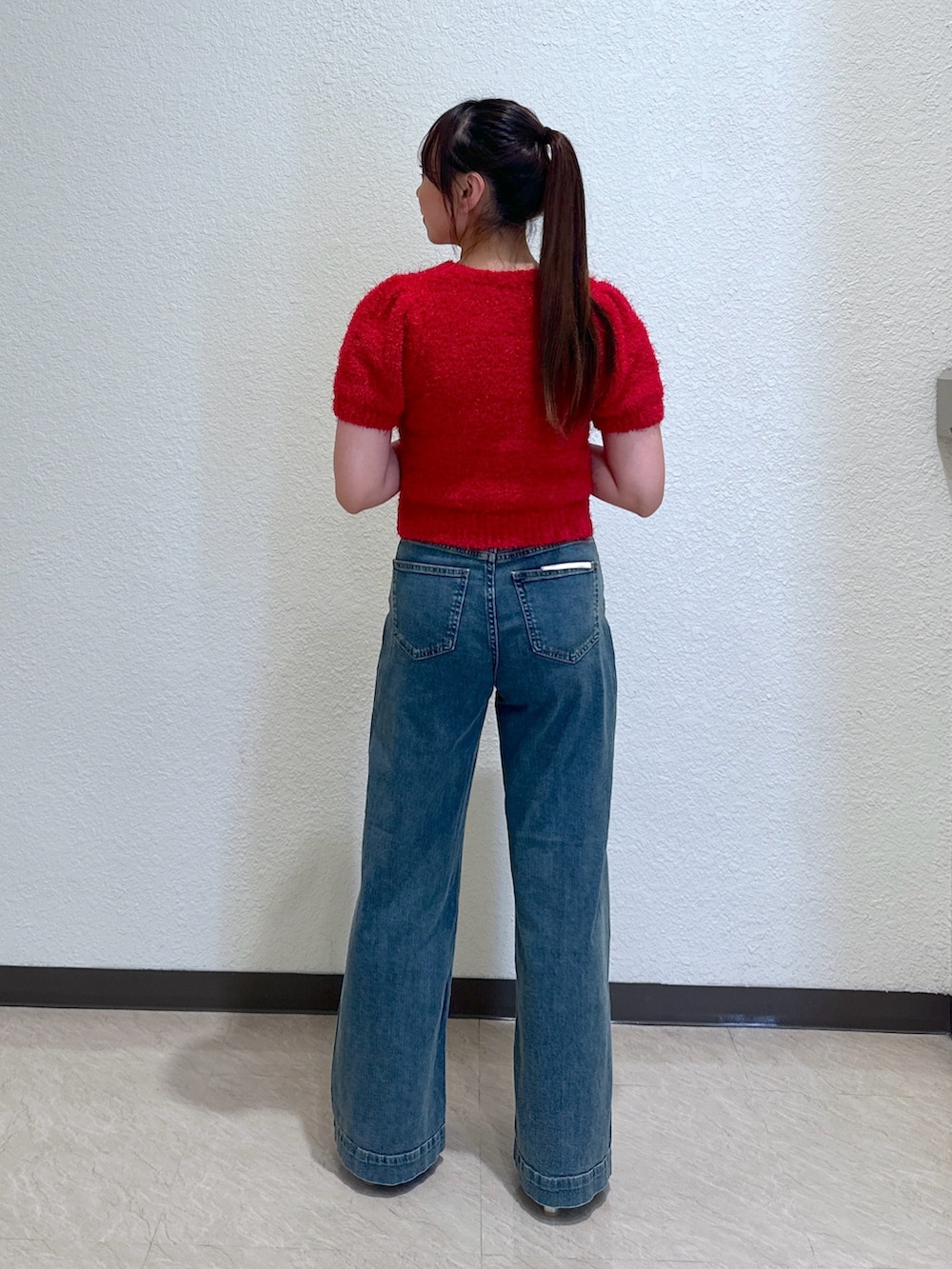 ブルー系のデニムパンツ、レッド系のニット/セーター、ホワイト系のトートバッグを着用したレディースの春コーディネートの3枚目の写真