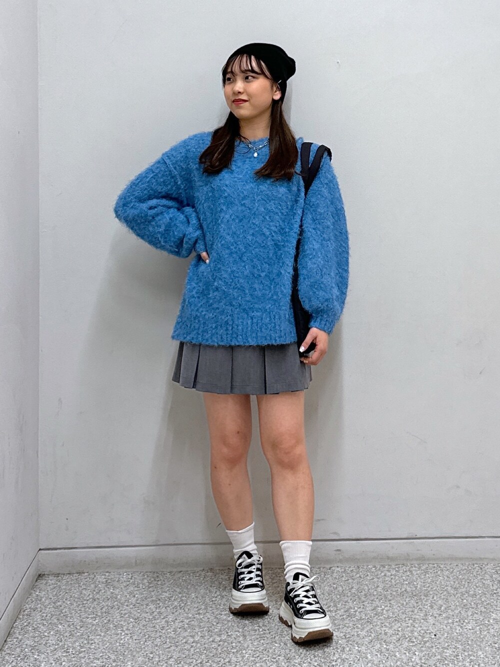 グレー系のスカート、ブラック系のトートバッグ、グリーン系のニット/セーターを着用したレディースの冬コーディネートの2枚目の写真