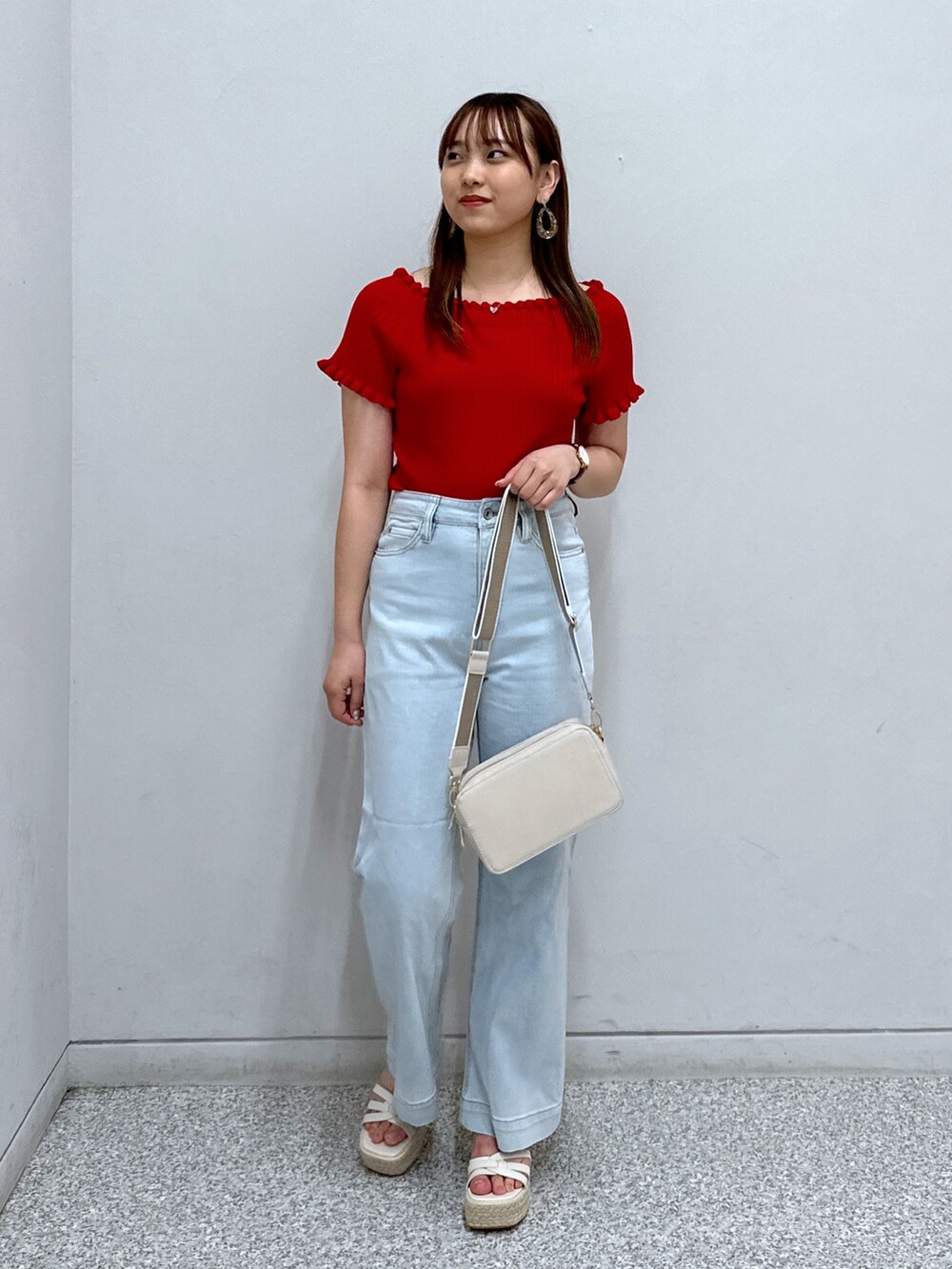 レッド系のニット/セーター、ホワイト系のショルダーバッグ、ブルー系のデニムパンツを着用したレディースの夏コーディネートの2枚目の写真