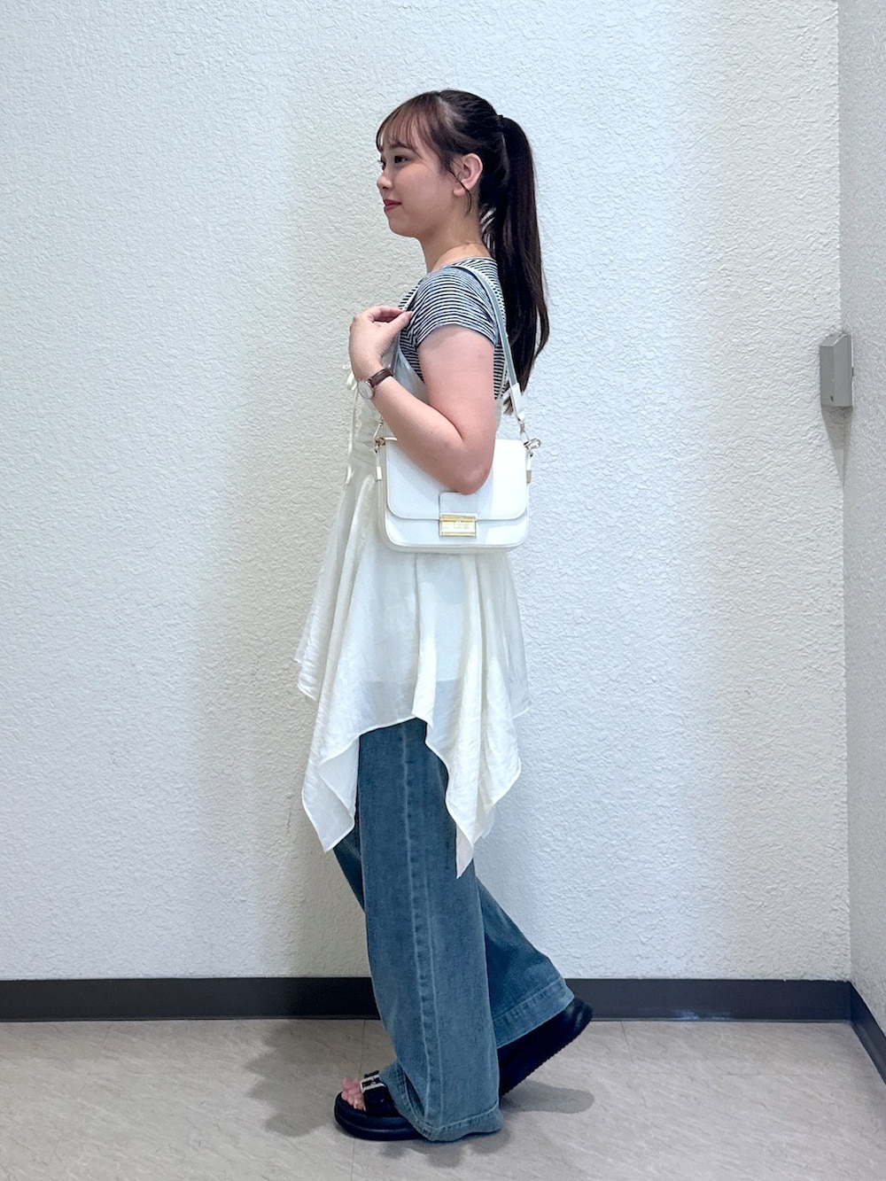 ホワイト系のワンピース、ブルー系のデニムパンツ、ブラック系のサンダルを着用したレディースの夏コーディネートの3枚目の写真