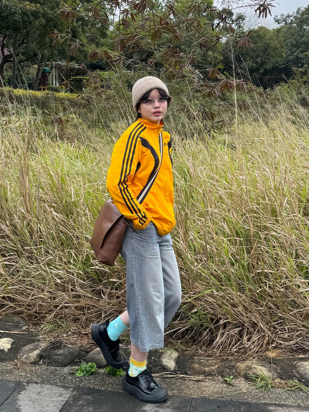 ブルー系のデニムパンツ、ブラック系のスニーカー、イエロー系のスタジャンを着用したレディースの夏コーディネートの2枚目の写真