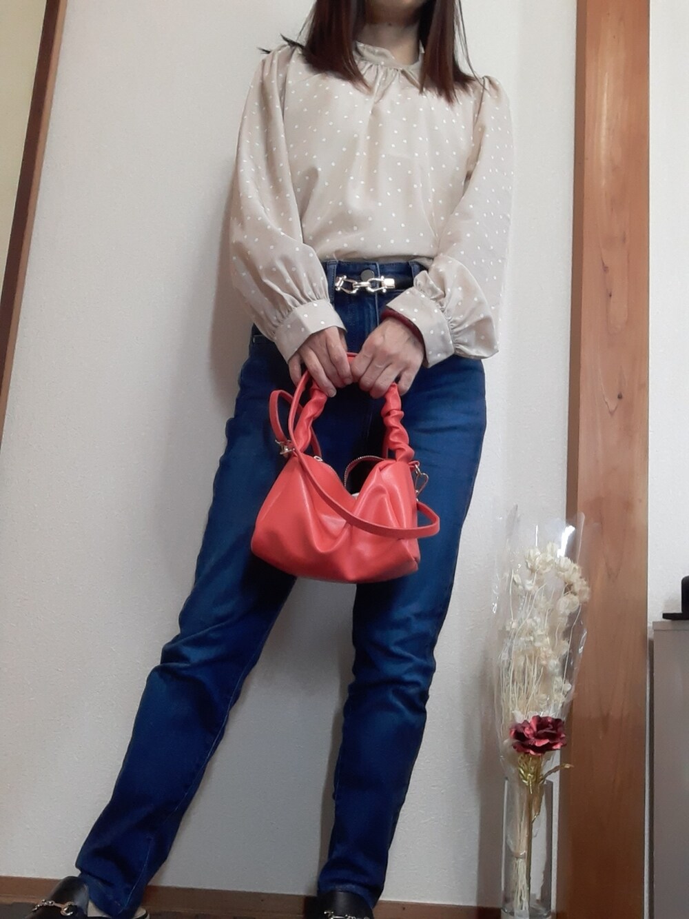 ベージュ系のトップス、ブルー系のパンツ、オレンジ系のバッグを着用したレディースの秋コーディネートの2枚目の写真