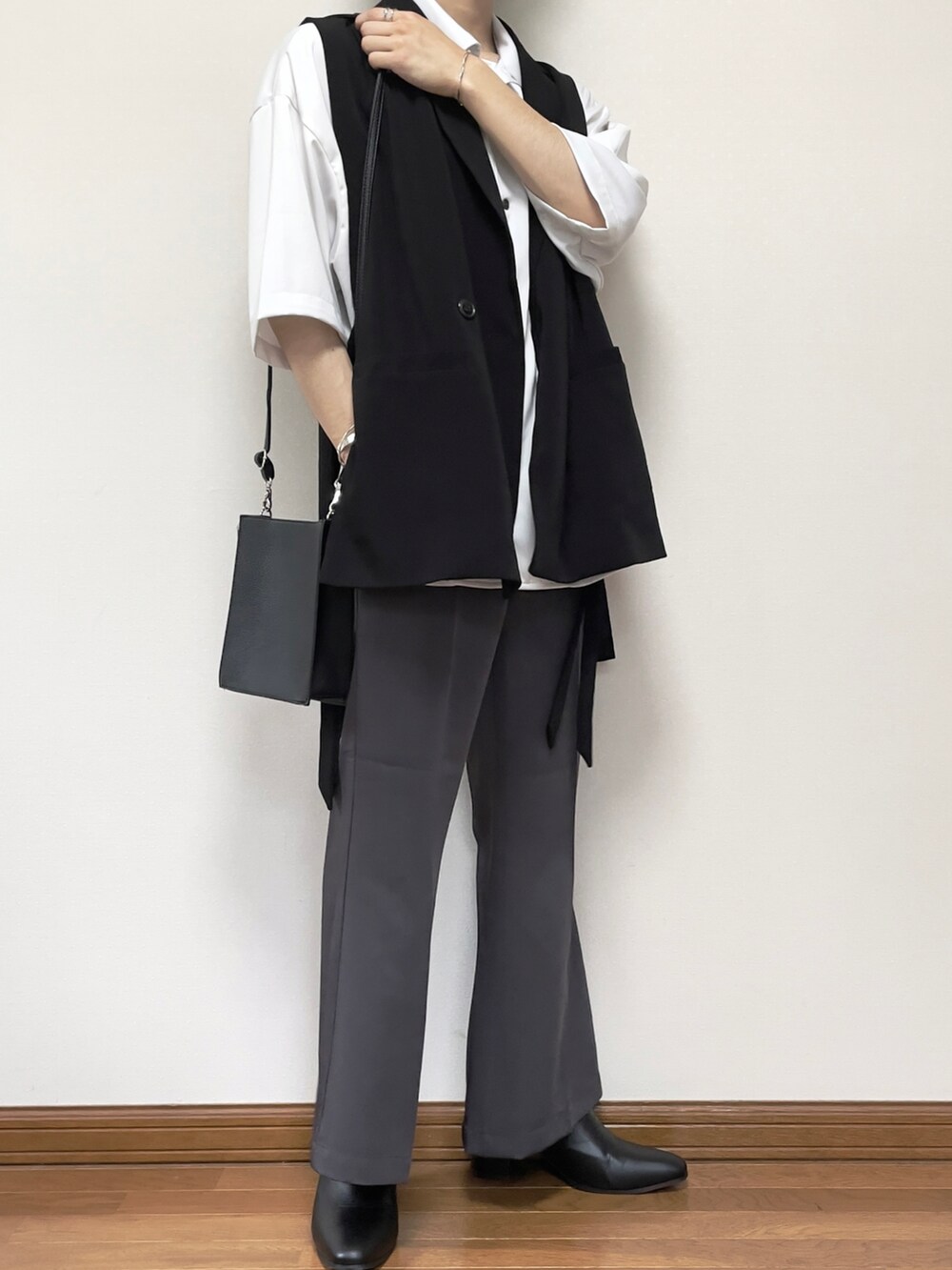 グレー系のスラックス、ブラック系のブーツ、ブラック系のショルダーバッグを着用したメンズの夏コーディネートの3枚目の写真