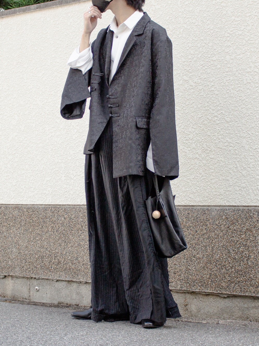 ブラック系のテーラードジャケット、ブラック系のトートバッグ、ブラック系のスラックスを着用したメンズの秋コーディネートの2枚目の写真