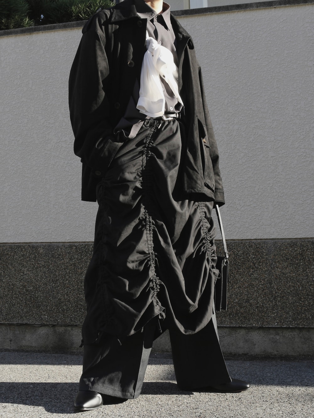 ブラック系のスカート、ブラック系のスラックス、ブラック系のショルダーバッグを着用したメンズの秋コーディネートの2枚目の写真