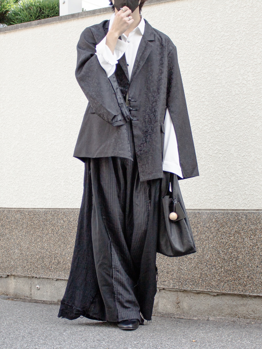 ブラック系のテーラードジャケット、ブラック系のトートバッグ、ブラック系のスラックスを着用したメンズの秋コーディネートの4枚目の写真