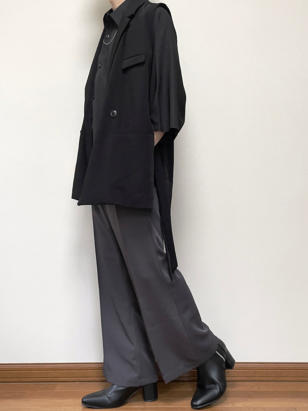 グレー系のスラックス、ブラック系のブーツ、ブラック系のベストを着用したメンズの夏コーディネートの2枚目の写真