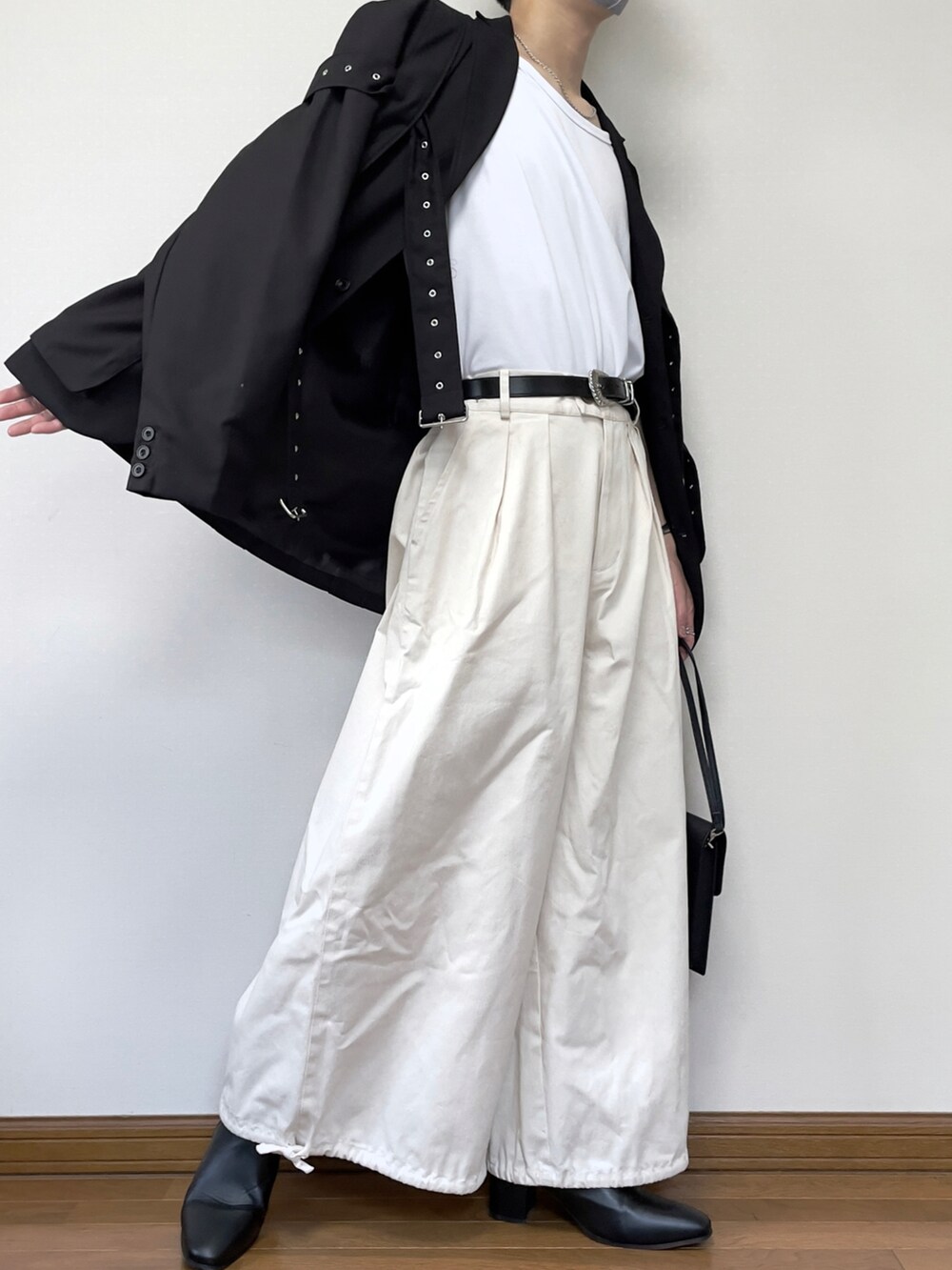 ブラック系のテーラードジャケット、ホワイト系のタンクトップ、ブラック系のショルダーバッグを着用したメンズの夏コーディネートの2枚目の写真