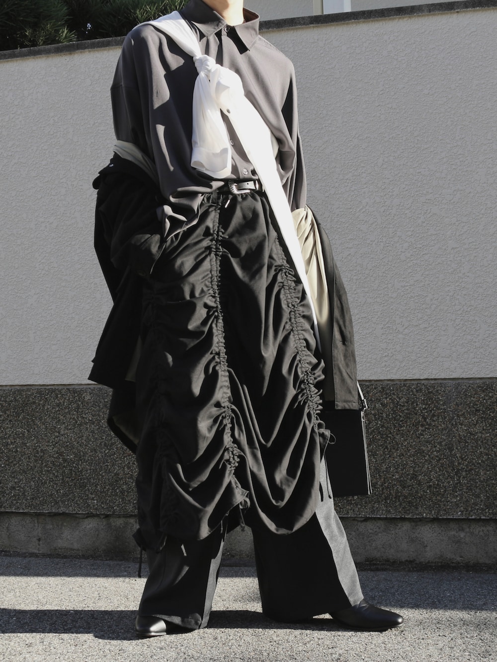 ブラック系のスカート、ブラック系のスラックス、ブラック系のショルダーバッグを着用したメンズの秋コーディネートの3枚目の写真