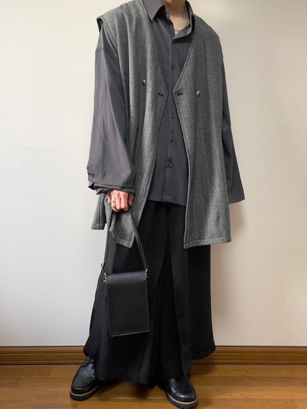 グレー系のシャツ/ブラウス、グレー系のベスト、ブラック系のショルダーバッグを着用したメンズの春コーディネートの2枚目の写真