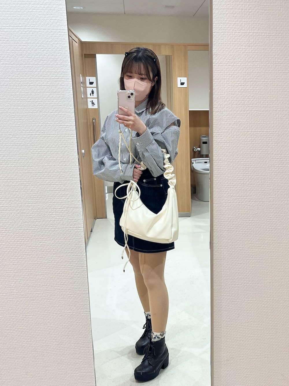 ブルー系のデニムスカート、ホワイト系のバッグ、グレー系のシャツ/ブラウスを着用したレディースの春コーディネートの2枚目の写真