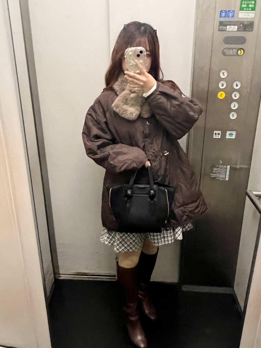 ブラウン系のノーカラージャケット、ブラック系のワンピース、ブラウン系のブーツを着用したレディースの冬コーディネートの2枚目の写真