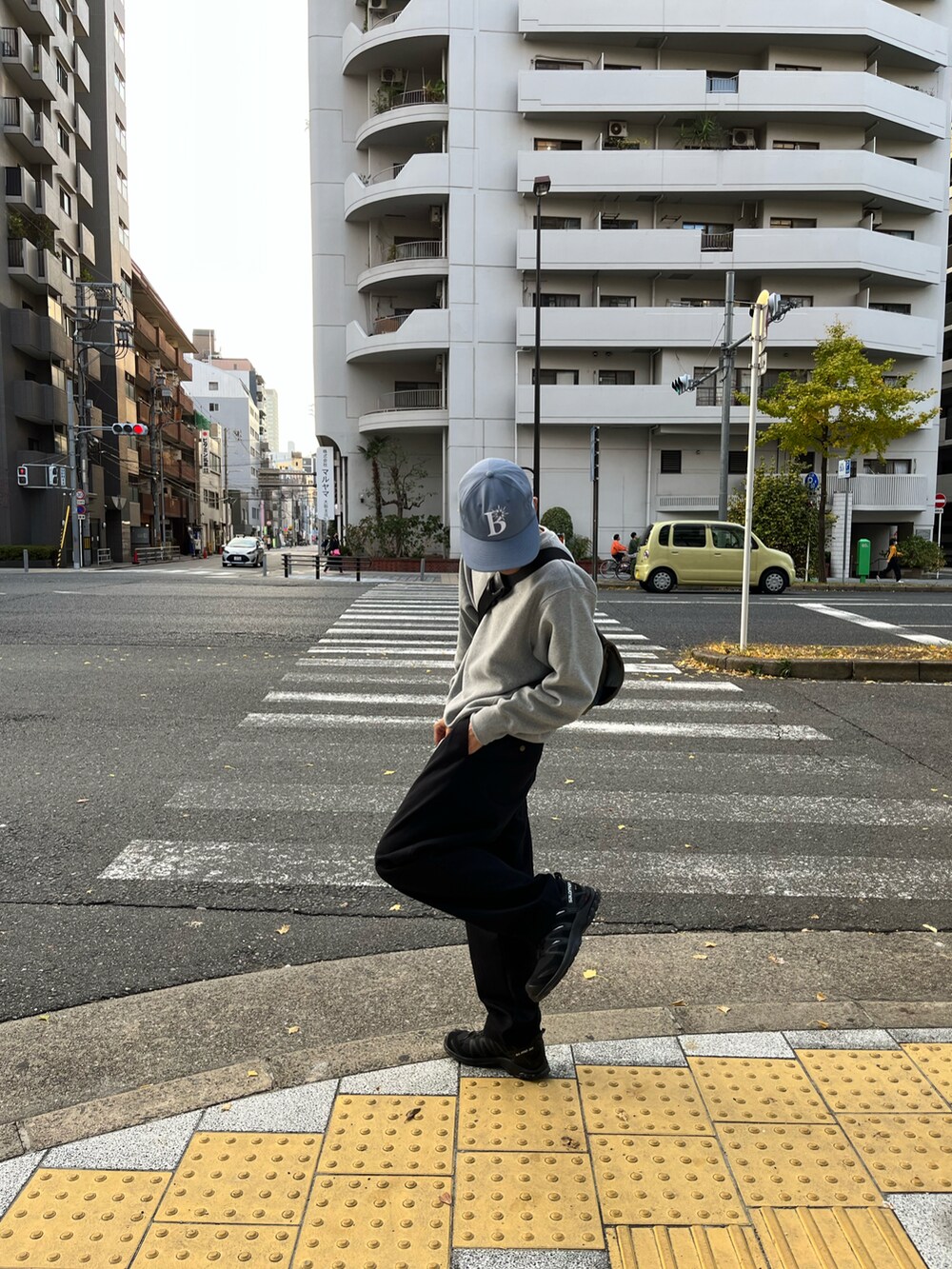 グレー系のスウェット、ブラック系のチノパンツ、ブラック系のスニーカーを着用したメンズの春コーディネートの2枚目の写真