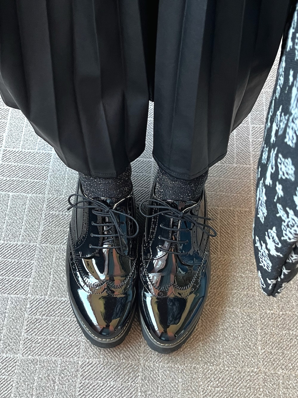 イエロー系のカーディガン/ボレロ、ブラック系のスカート、ブラック系のシューズを着用したレディースの秋コーディネートの2枚目の写真