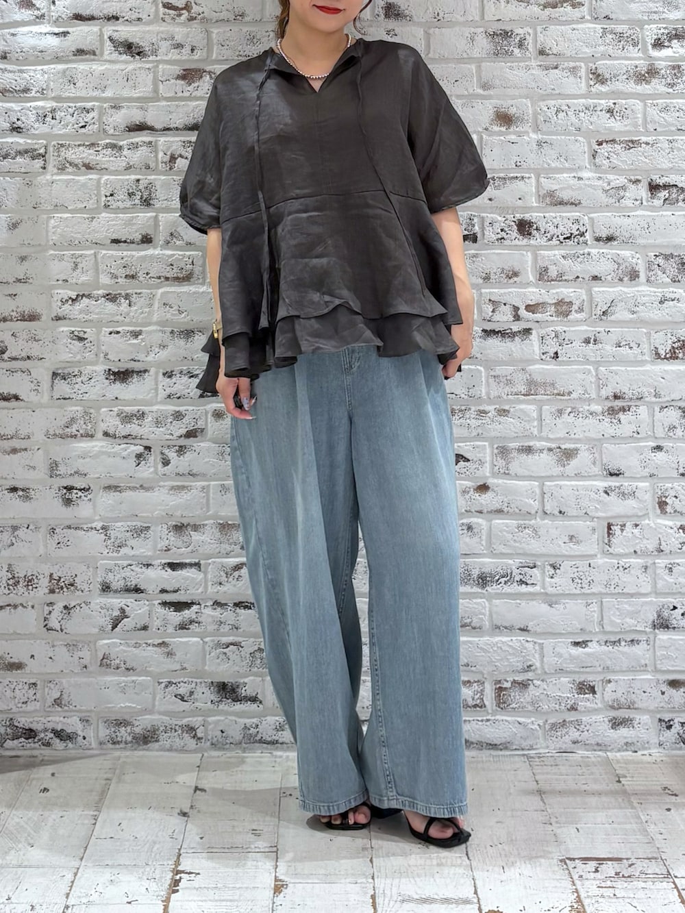 ブラック系のシャツ/ブラウス、ブルー系のデニムパンツ、ブラック系のサンダルを着用したレディースの夏コーディネートの2枚目の写真