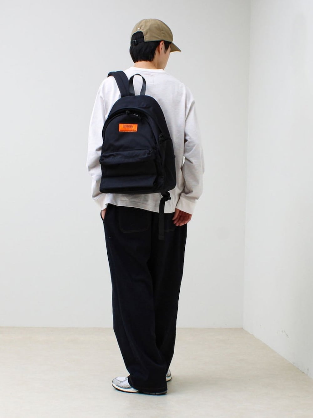 ブラック系のバックパック/リュック、ホワイト系のTシャツ/カットソー、ベージュ系のキャップを着用したメンズの春コーディネートの2枚目の写真