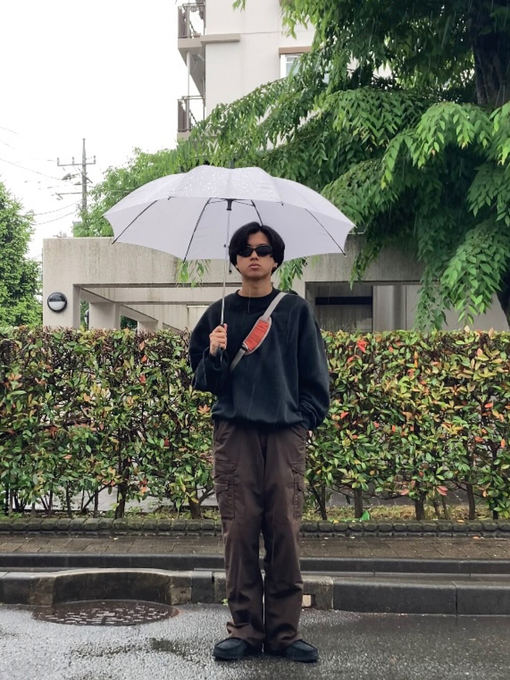 ブラウン系のカーゴパンツ、ブラック系のスウェット、ブラック系のモカシン/デッキシューズを着用したメンズの春コーディネートの2枚目の写真