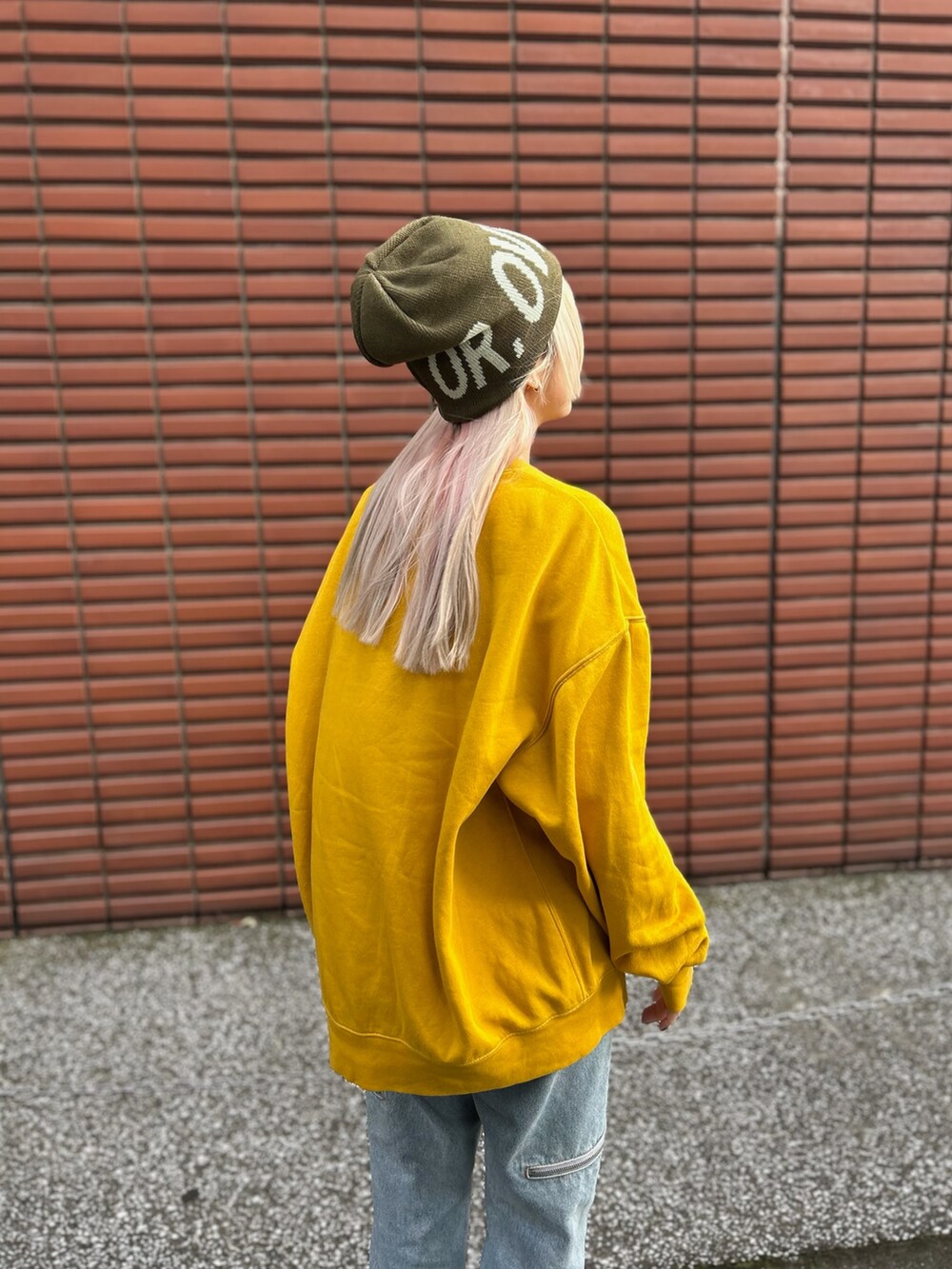イエロー系のスウェット、ブルー系のデニムパンツ、ブラウン系のスニーカーを着用したレディースの冬コーディネートの2枚目の写真