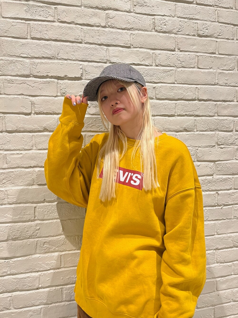 イエロー系のスウェット、ブラウン系のパンツ、ホワイト系のスニーカーを着用したレディースの冬コーディネートの2枚目の写真