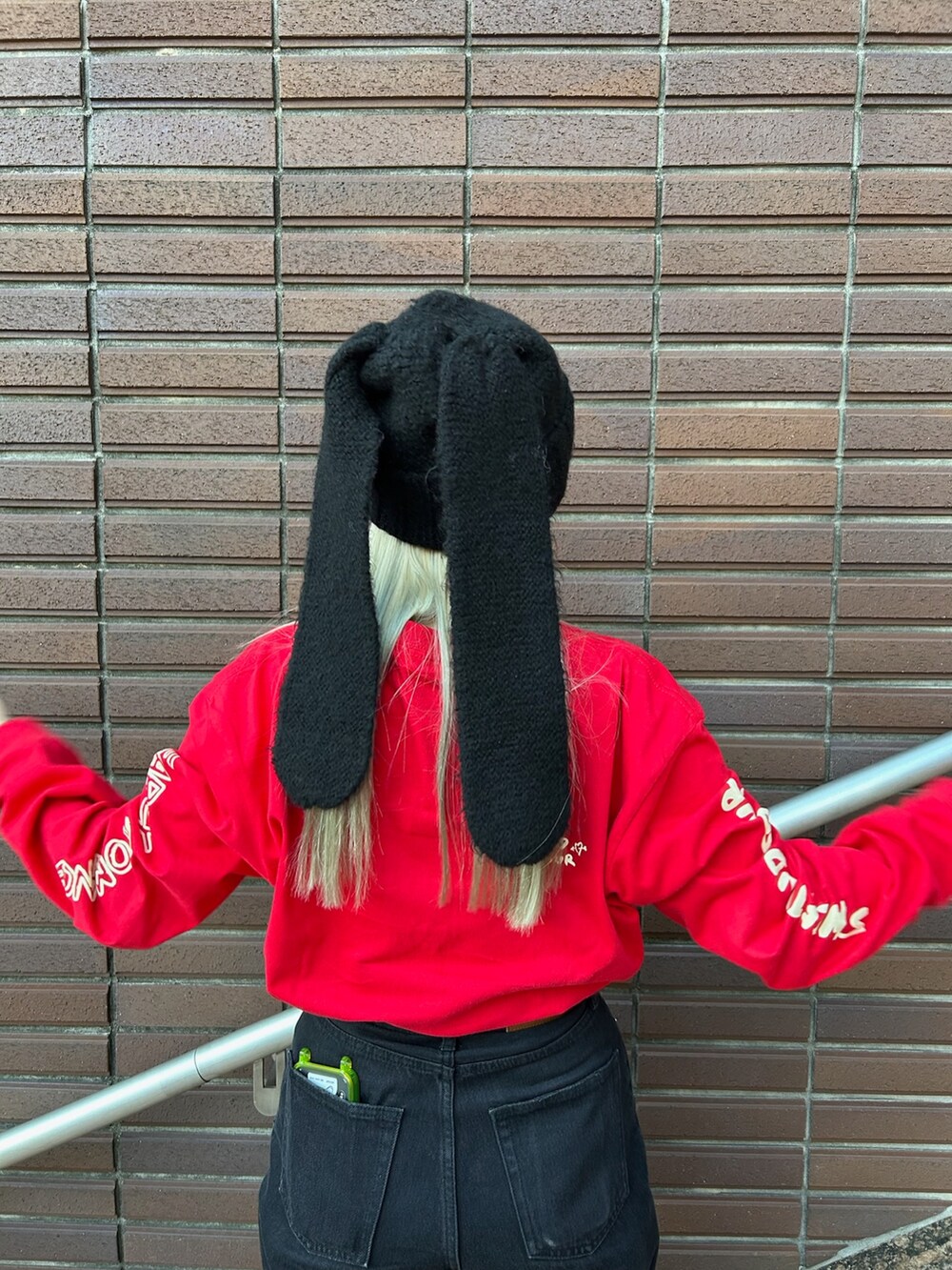 レッド系のTシャツ/カットソー、ブラック系のニットキャップ/ビーニーを着用したレディースの秋コーディネートの4枚目の写真