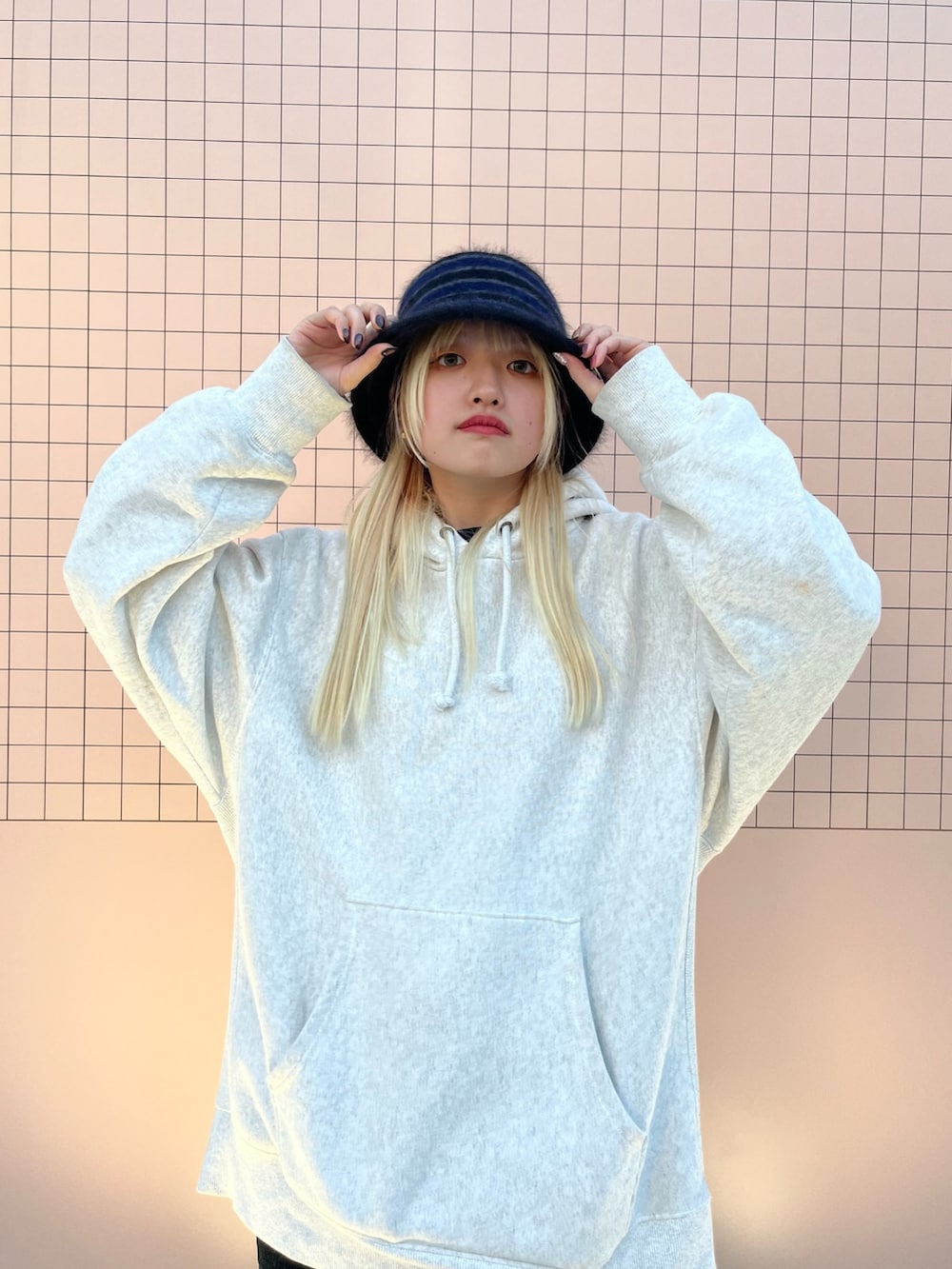 グレー系のパーカー、ブラウン系のスニーカー、ブラック系のハットを着用したレディースの冬コーディネートの2枚目の写真