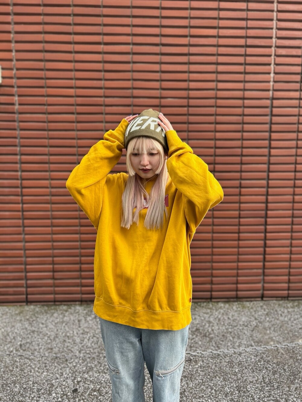 イエロー系のスウェット、ブルー系のデニムパンツ、ブラウン系のスニーカーを着用したレディースの冬コーディネートの3枚目の写真