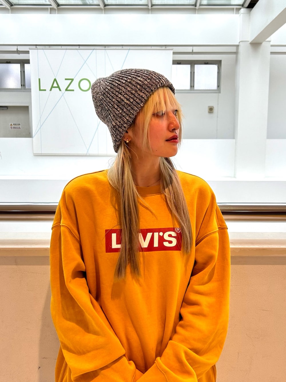 イエロー系のスウェット、ブルー系のデニムパンツ、ブラウン系のスニーカーを着用したレディースの冬コーディネートの2枚目の写真