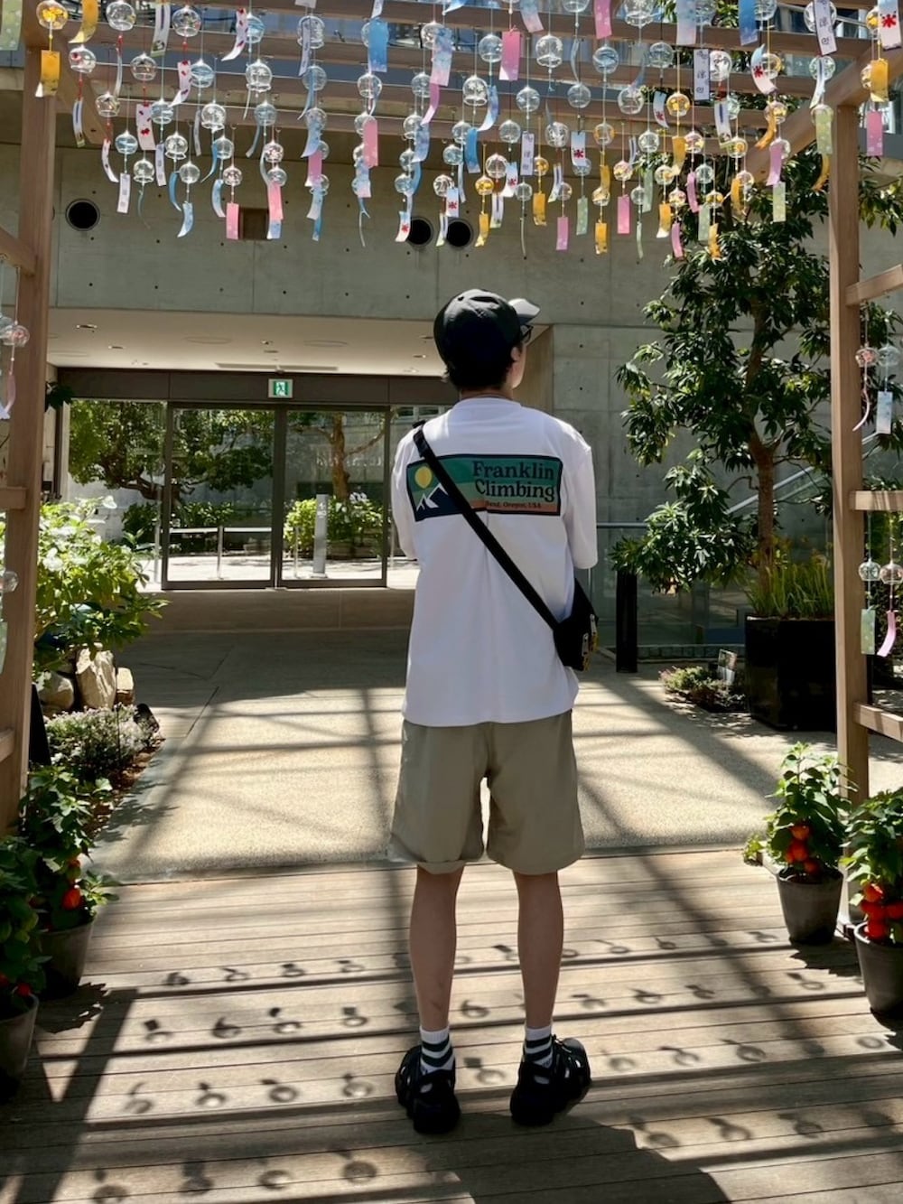 ホワイト系のTシャツ/カットソー、ベージュ系のその他パンツ、ブラック系のボディバッグ/ウエストポーチを着用したメンズの夏コーディネートの2枚目の写真