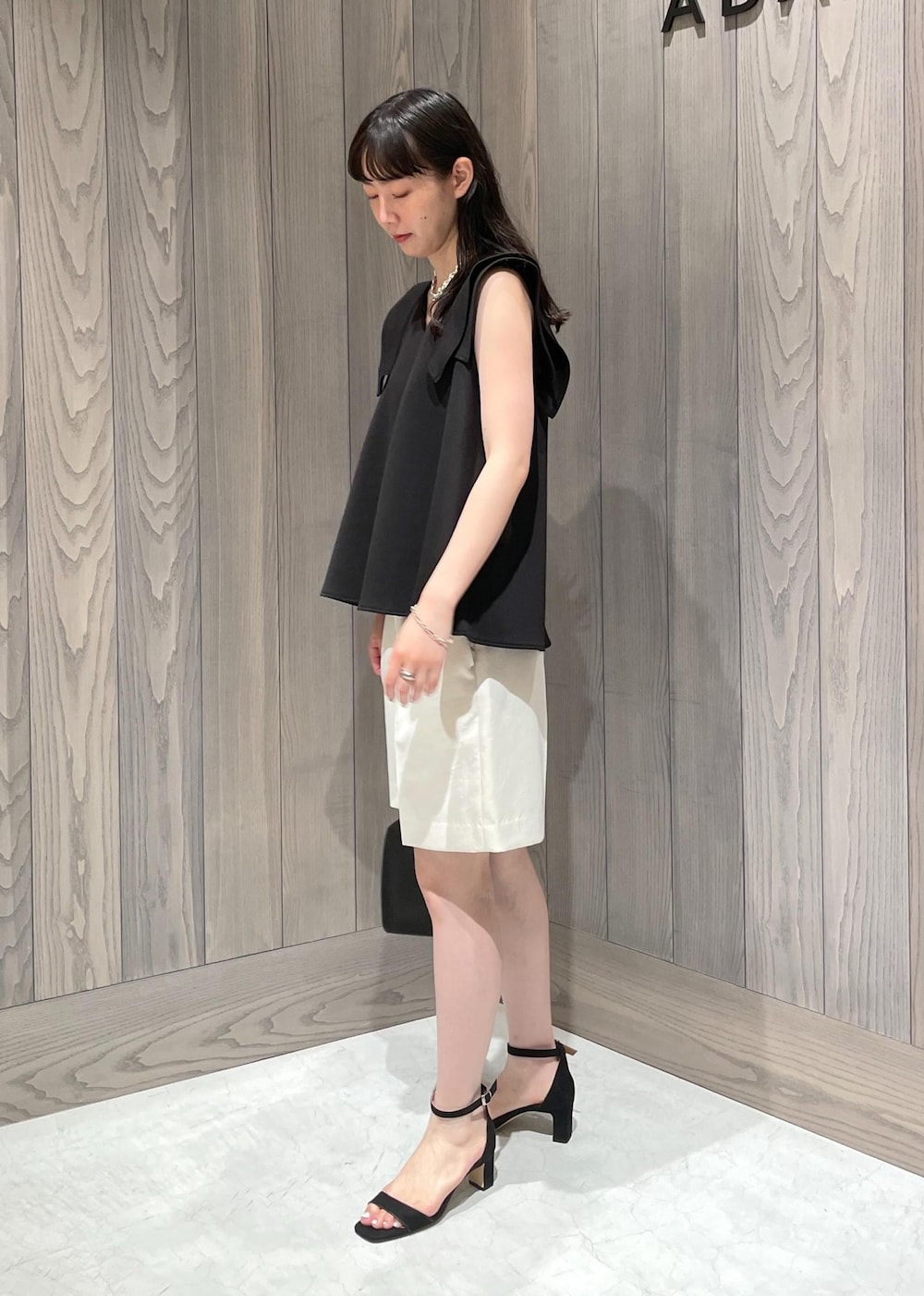 ブラック系のハンドバッグ、ブラック系のサンダル、ホワイト系のその他パンツを着用したレディースの夏コーディネートの2枚目の写真