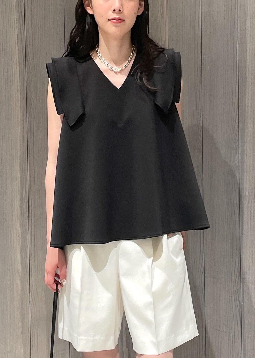 ブラック系のハンドバッグ、ブラック系のサンダル、ホワイト系のその他パンツを着用したレディースの夏コーディネートの6枚目の写真