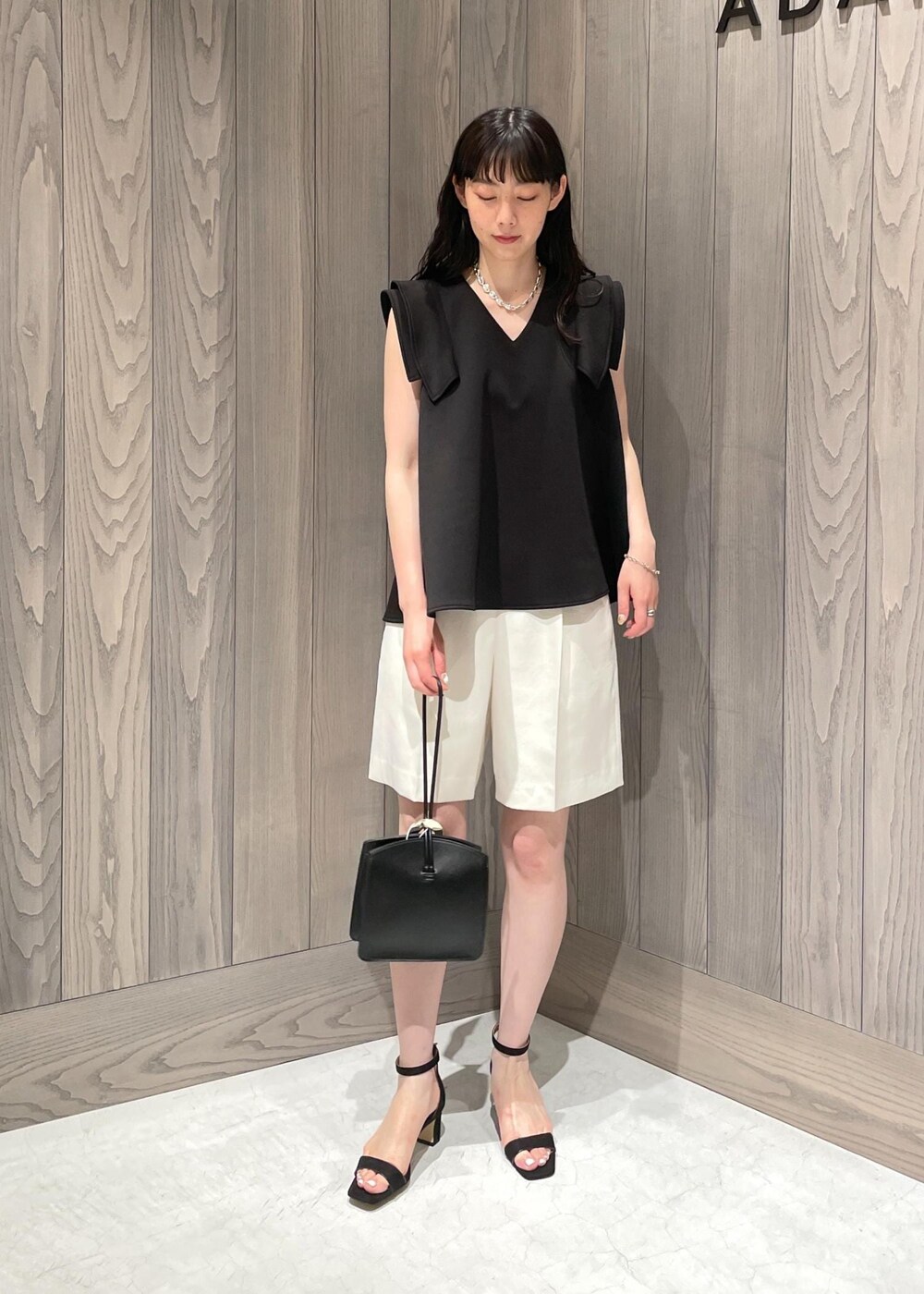 ブラック系のハンドバッグ、ブラック系のサンダル、ホワイト系のその他パンツを着用したレディースの夏コーディネートの7枚目の写真