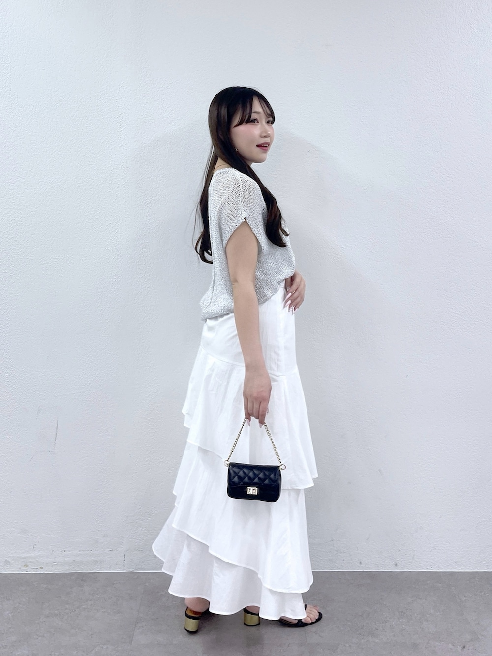 ホワイト系のスカート、シルバー系のニット/セーター、ブラック系のトートバッグを着用したレディースの春コーディネートの3枚目の写真