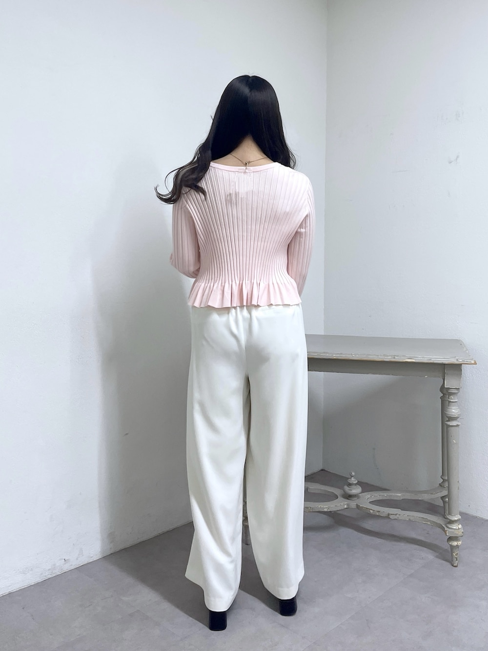 ピンク系のニット/セーター、ホワイト系のスラックス、ブラック系のブーツを着用したレディースの秋コーディネートの6枚目の写真