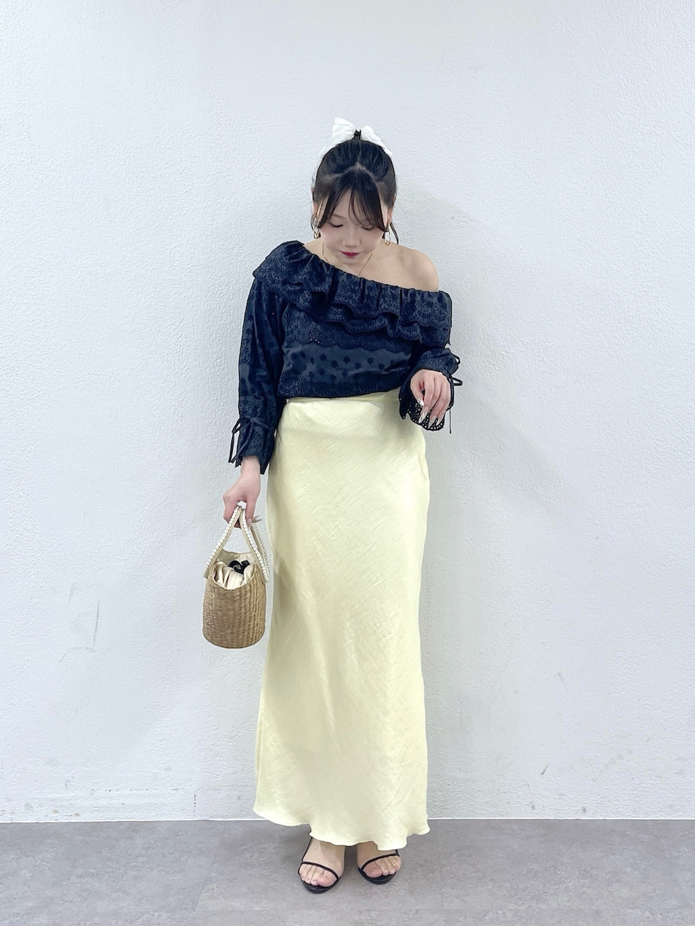 ベージュ系のかごバッグ、イエロー系のスカート、ブルー系のシャツ/ブラウスを着用したレディースの春コーディネートの2枚目の写真