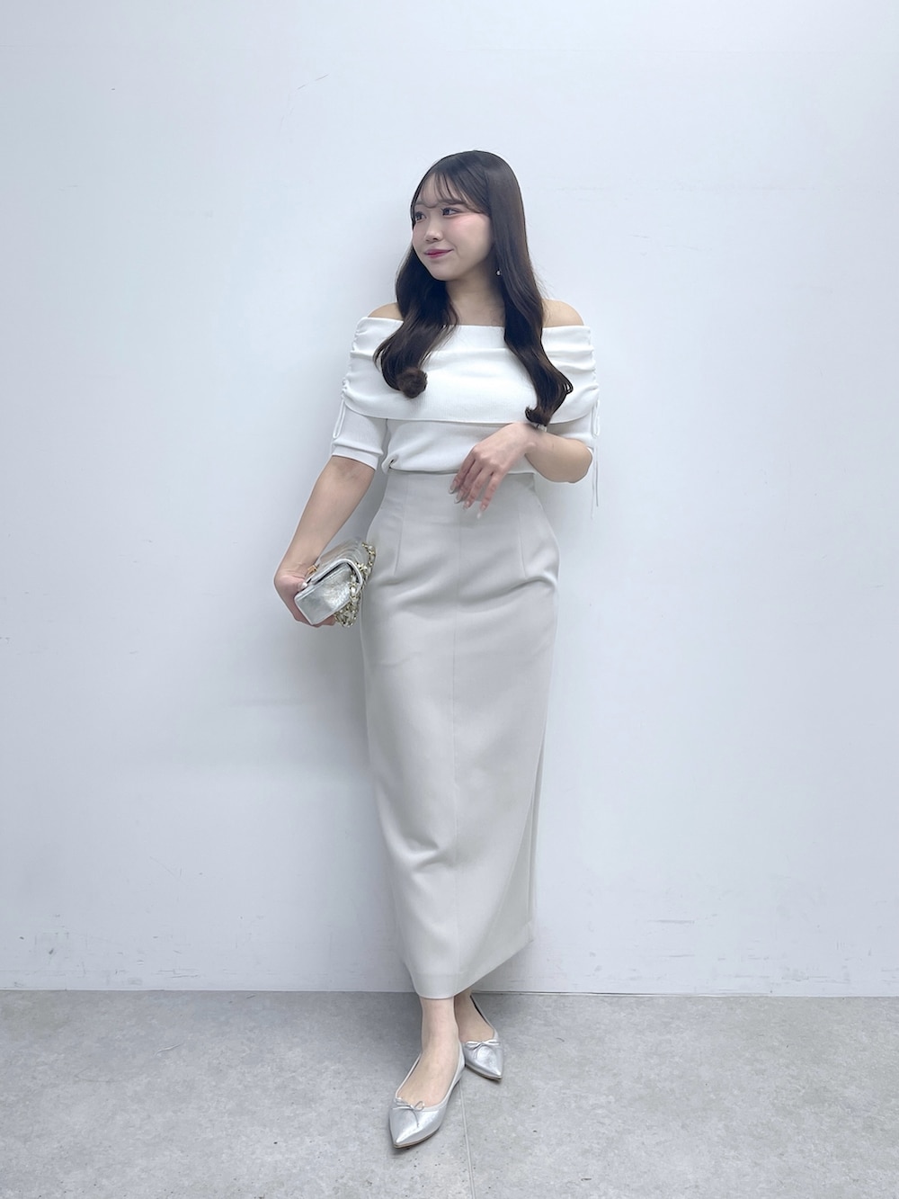 ホワイト系のニット/セーター、グレー系のスカートを着用したレディースの春コーディネートの2枚目の写真