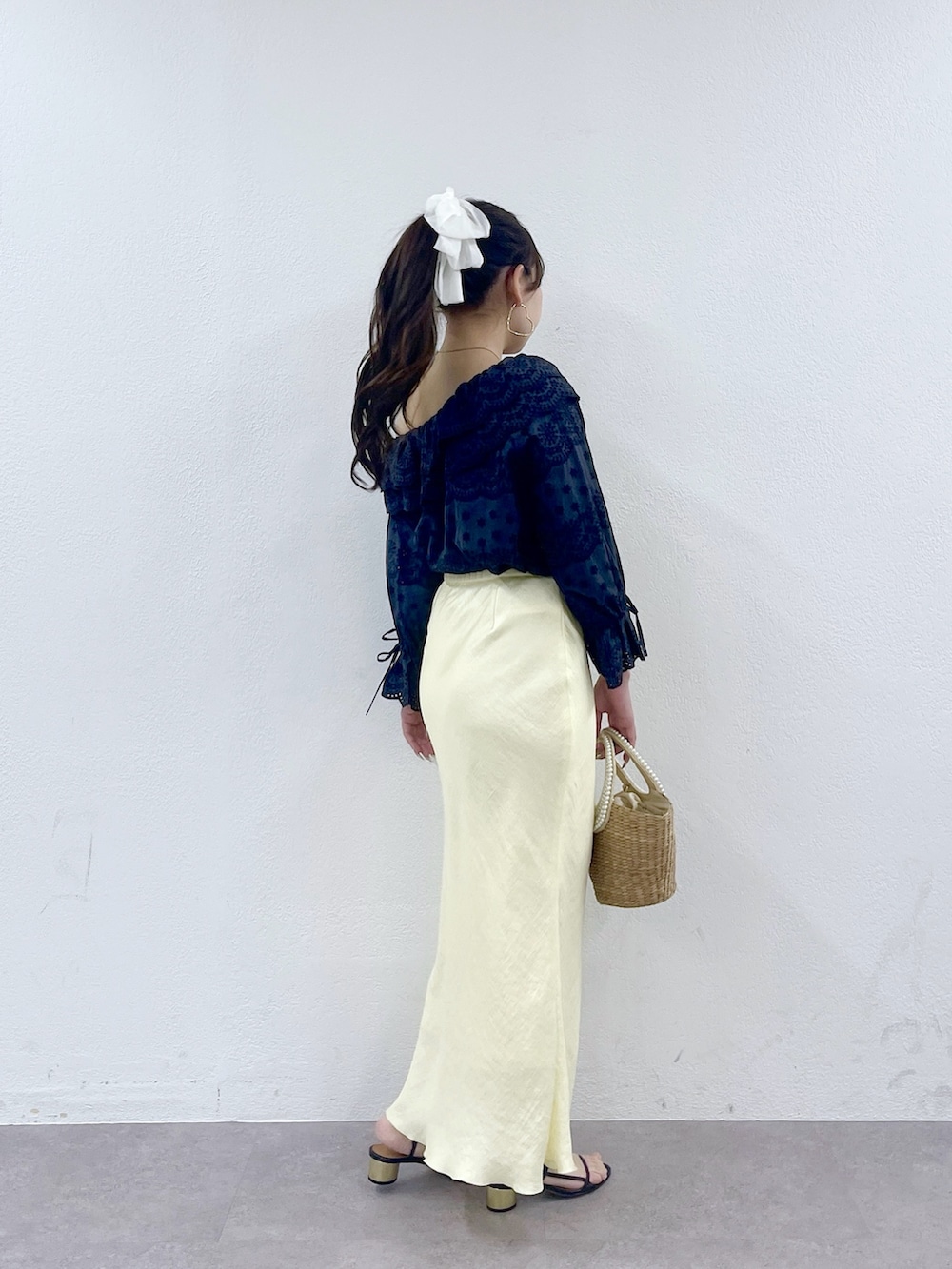 ベージュ系のかごバッグ、イエロー系のスカート、ブルー系のシャツ/ブラウスを着用したレディースの春コーディネートの3枚目の写真