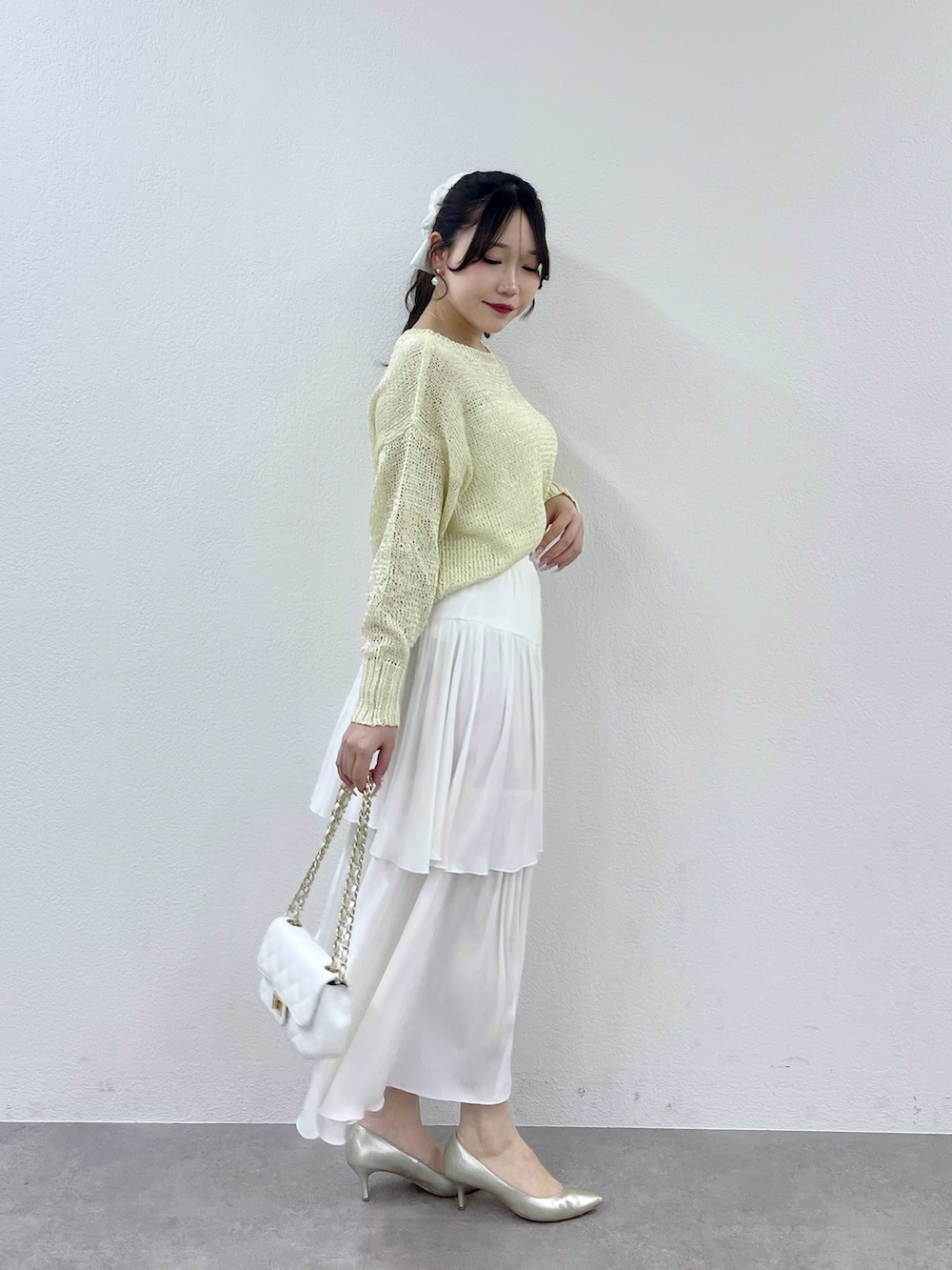 ホワイト系のハンドバッグ、ホワイト系のスカート、イエロー系のニット/セーターを着用したレディースの冬コーディネートの3枚目の写真