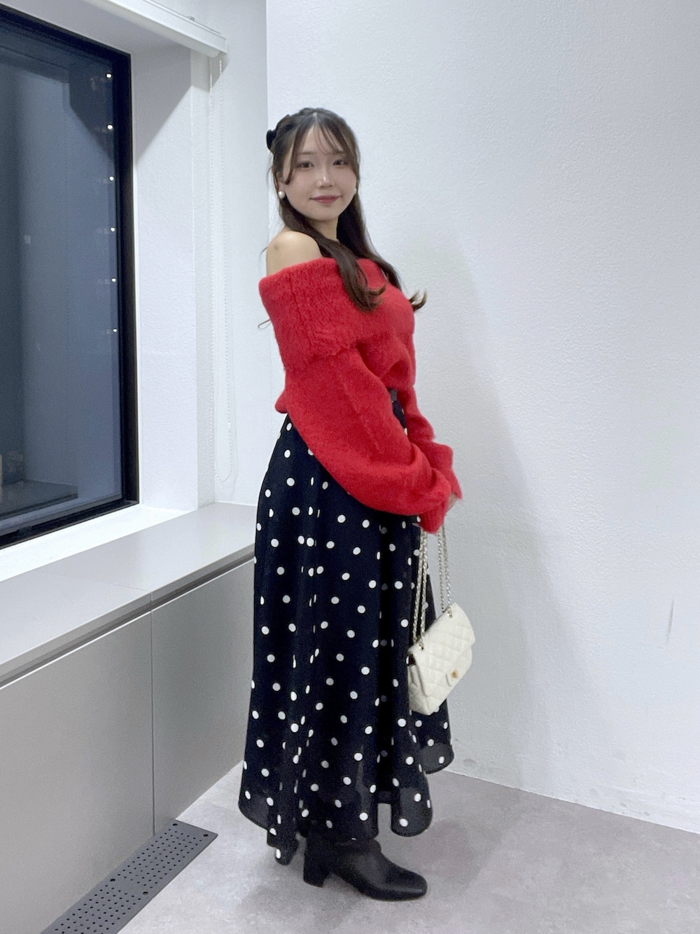 ブルー系のスカート、レッド系のニット/セーター、ゴールド系のネックレスを着用したレディースの秋コーディネートの3枚目の写真