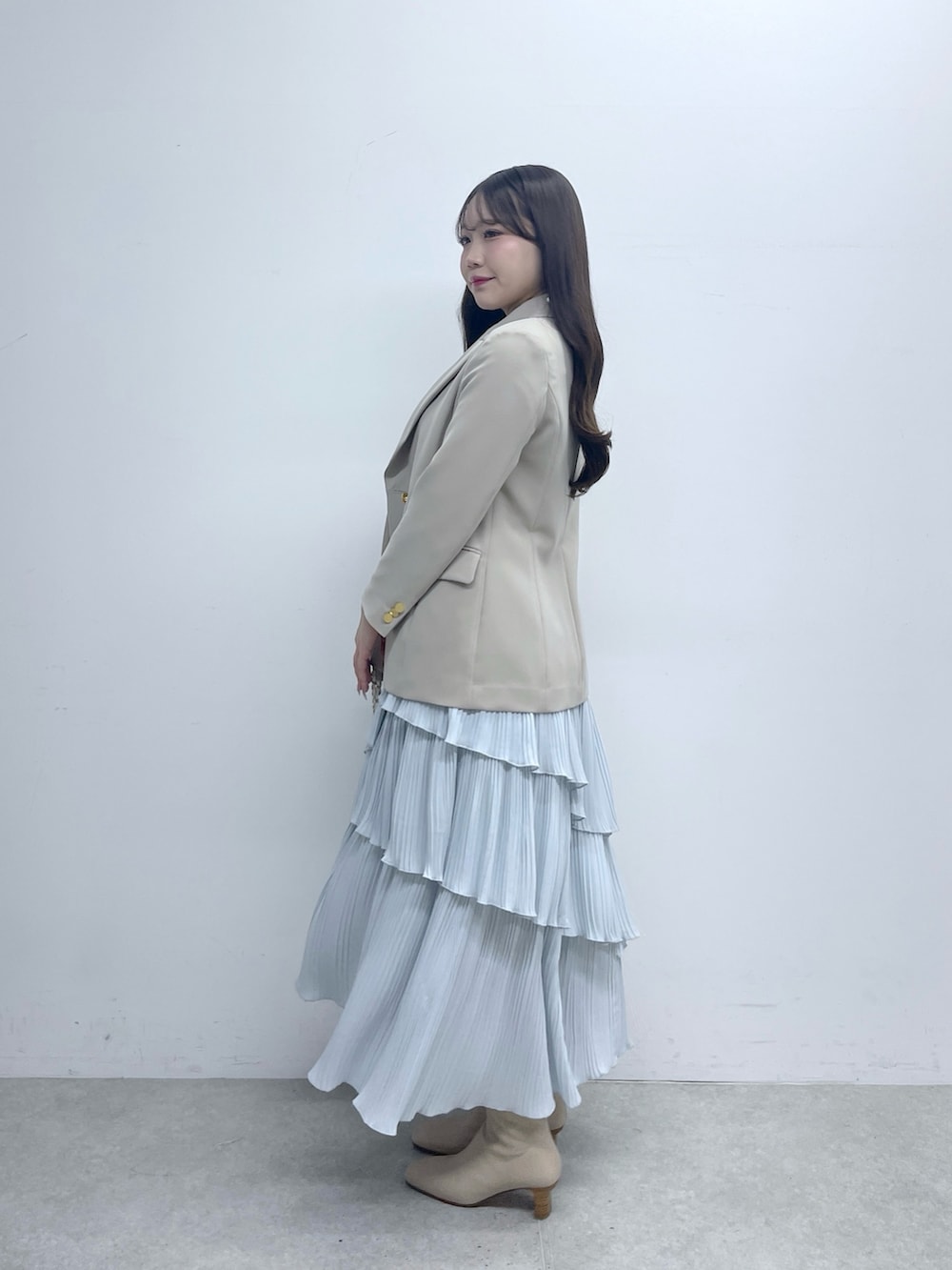 ベージュ系のテーラードジャケット、ホワイト系のニット/セーター、ブルー系のスカートを着用したレディースの春コーディネートの3枚目の写真