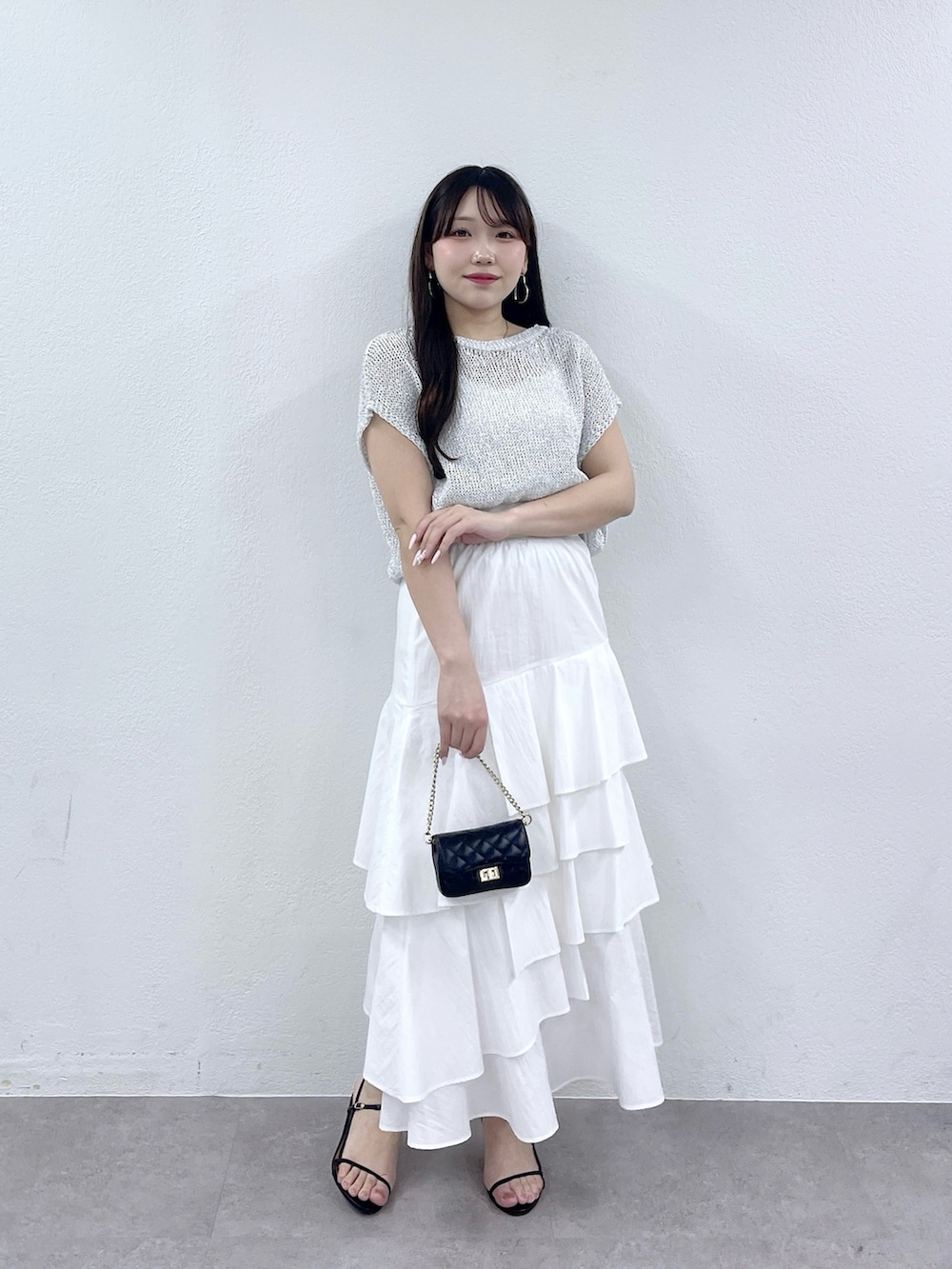 ホワイト系のスカート、シルバー系のニット/セーター、ブラック系のトートバッグを着用したレディースの春コーディネートの4枚目の写真
