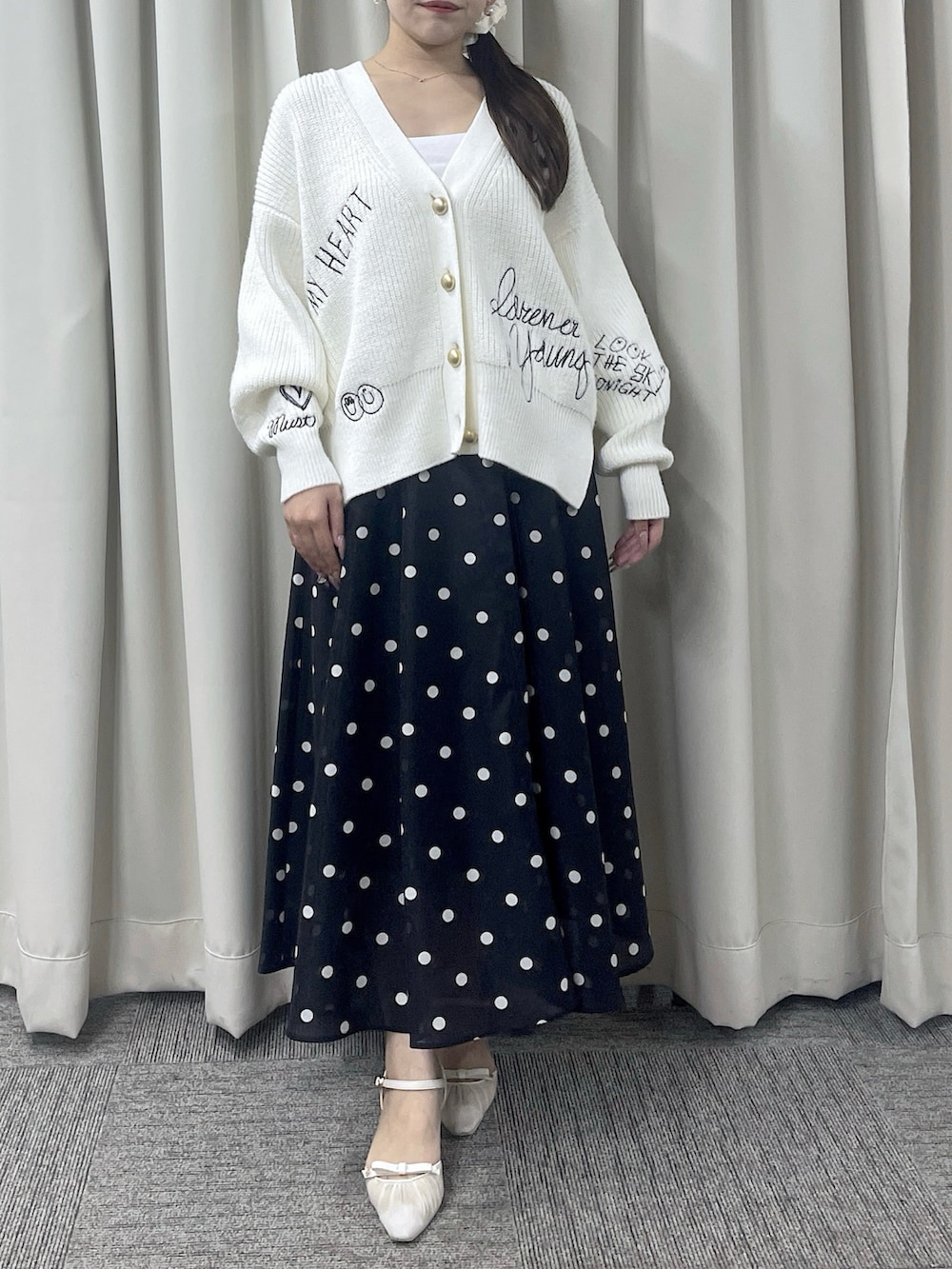 ブルー系のスカート、ホワイト系のカーディガン/ボレロを着用したレディースの秋コーディネートの2枚目の写真