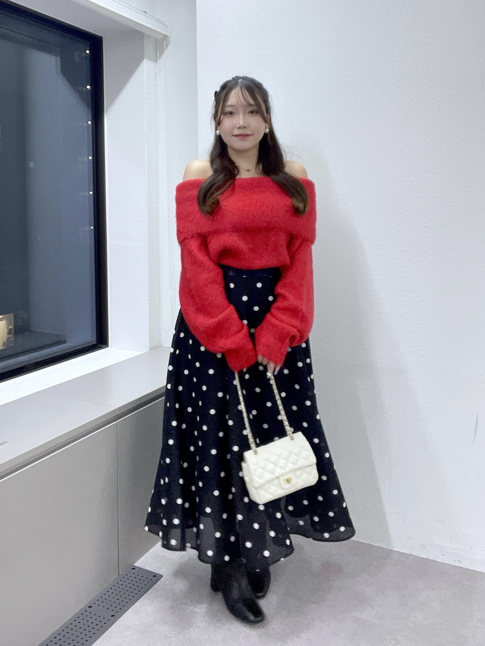 ブルー系のスカート、レッド系のニット/セーター、ゴールド系のネックレスを着用したレディースの秋コーディネートの2枚目の写真