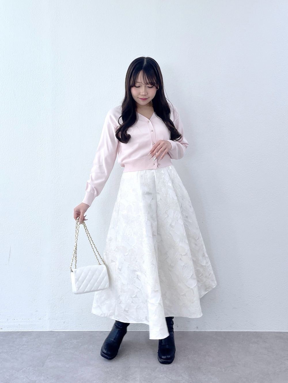 ピンク系のカーディガン/ボレロ、ホワイト系のスカートを着用したレディースの冬コーディネートの3枚目の写真