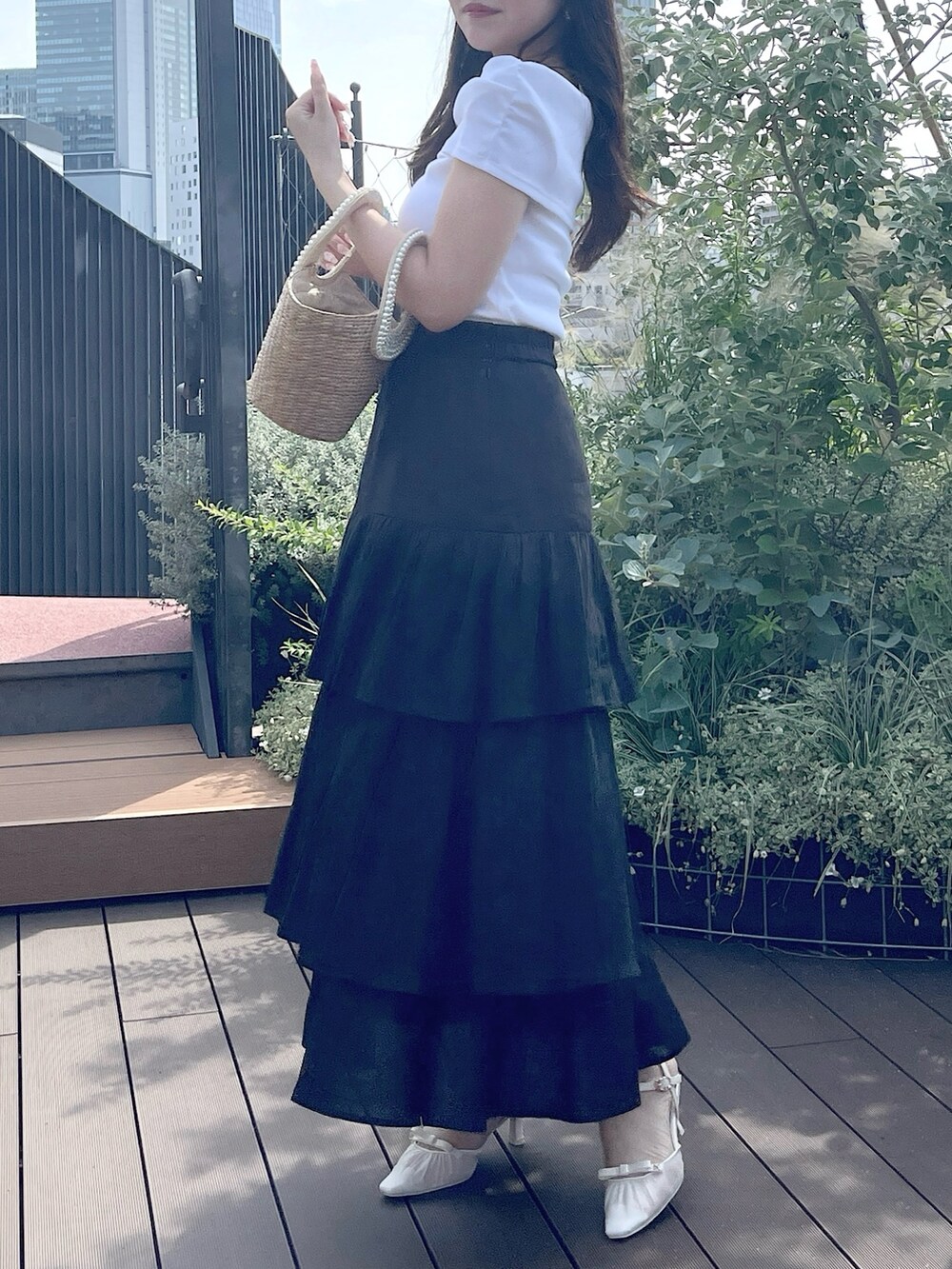 ブラック系のスカート、ベージュ系のかごバッグ、ホワイト系のTシャツ/カットソーを着用したレディースの夏コーディネートの2枚目の写真