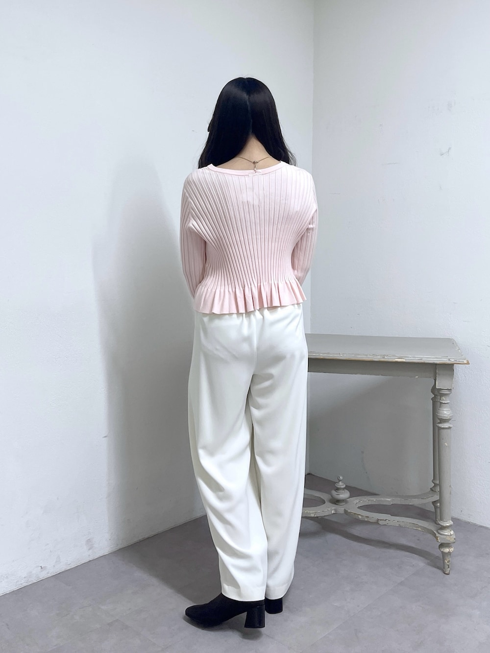 ピンク系のニット/セーター、ホワイト系のスラックス、ブラック系のブーツを着用したレディースの秋コーディネートの5枚目の写真