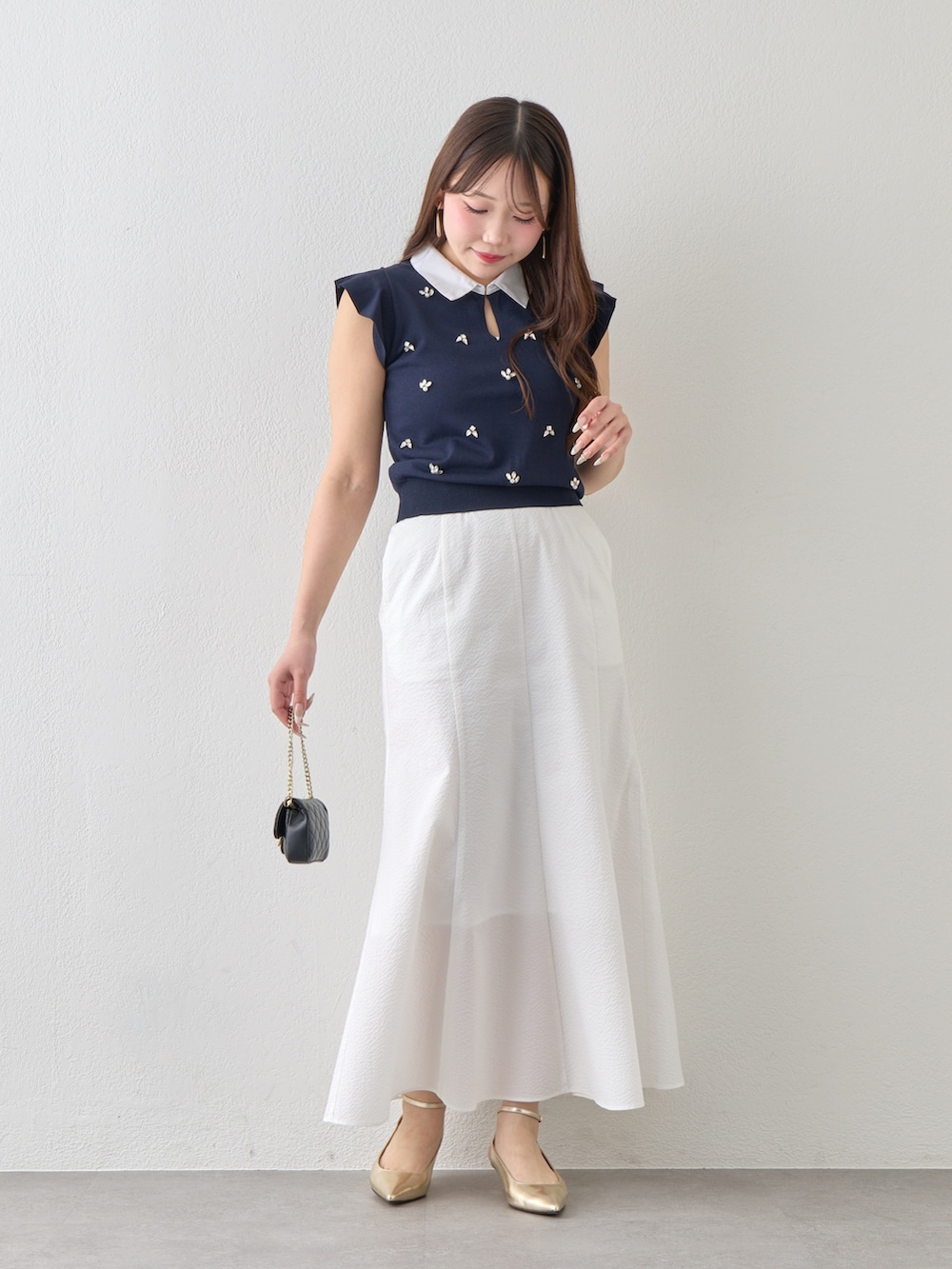 ブルー系のニット/セーター、ホワイト系のスカートを着用したレディースの春コーディネートの2枚目の写真