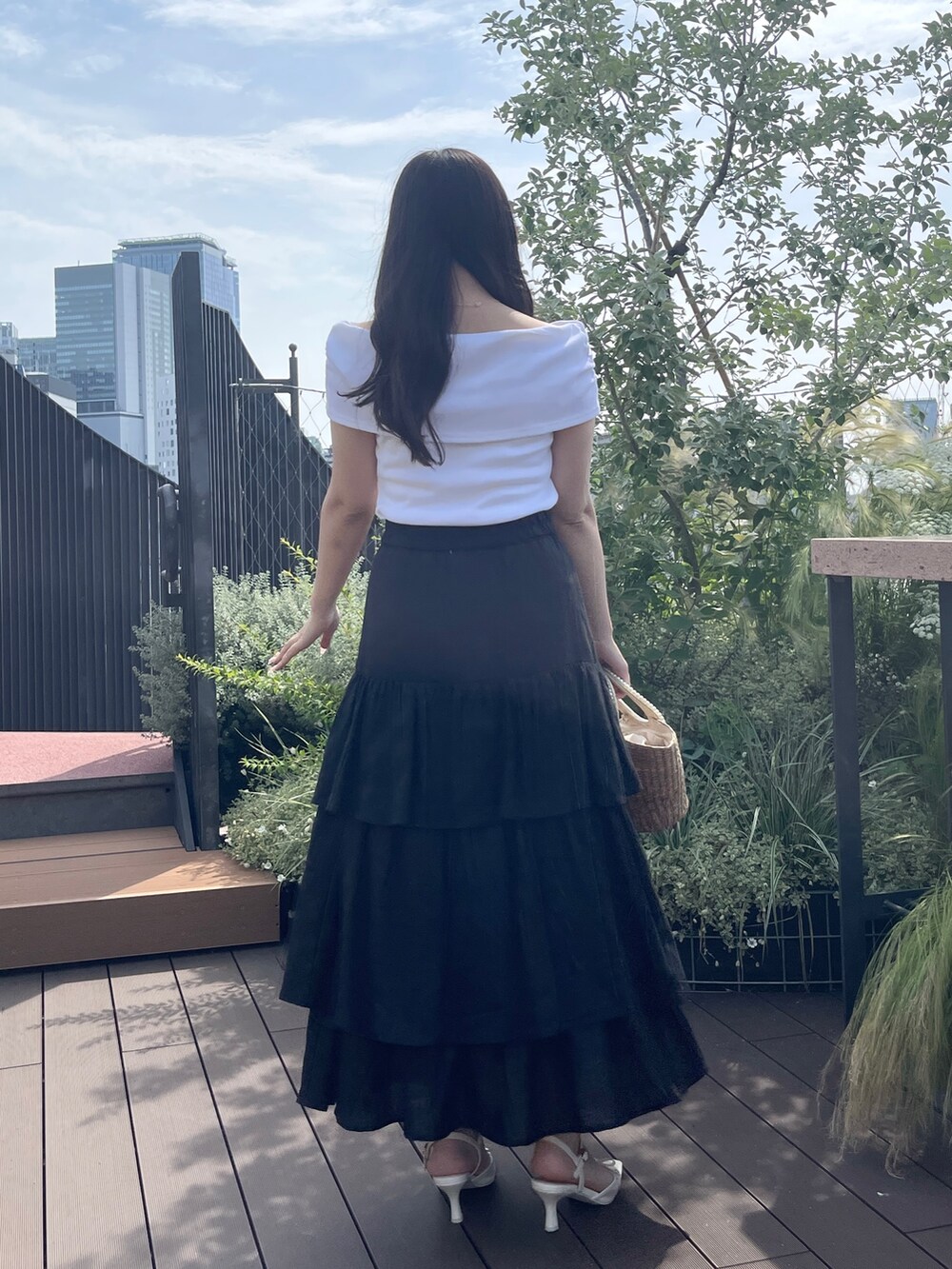 ブラック系のスカート、ベージュ系のかごバッグ、ホワイト系のTシャツ/カットソーを着用したレディースの夏コーディネートの4枚目の写真