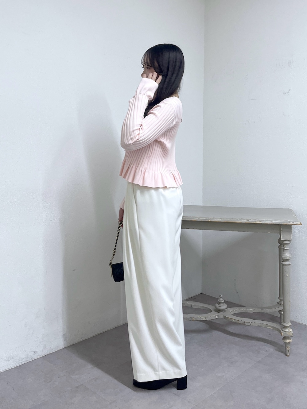 ピンク系のニット/セーター、ホワイト系のスラックス、ブラック系のブーツを着用したレディースの秋コーディネートの4枚目の写真